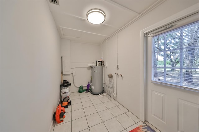 laundry area featuring water heater and light tile flooring