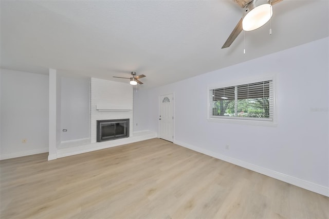 unfurnished living room with a fireplace, ceiling fan, and light hardwood / wood-style floors