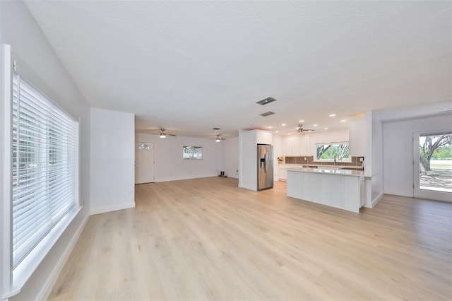 unfurnished living room with light hardwood / wood-style flooring and ceiling fan