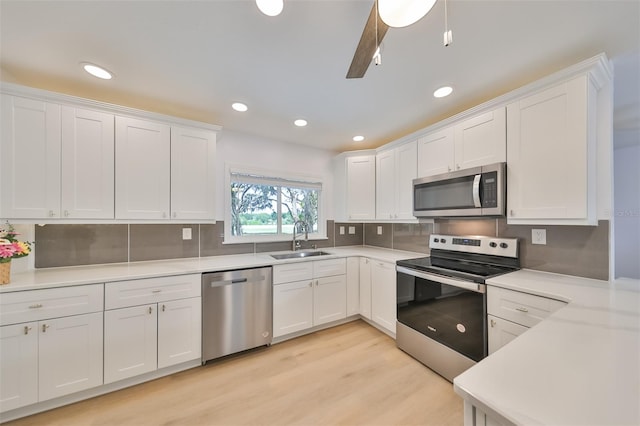 kitchen with white cabinets, light wood-type flooring, appliances with stainless steel finishes, sink, and tasteful backsplash