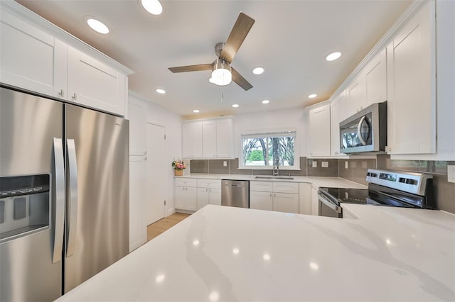 kitchen with white cabinets, backsplash, light wood-type flooring, and stainless steel appliances