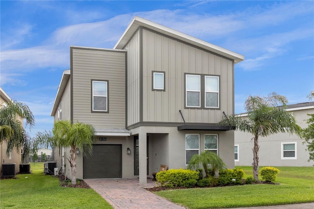 view of front of house with central AC, a garage, and a front lawn