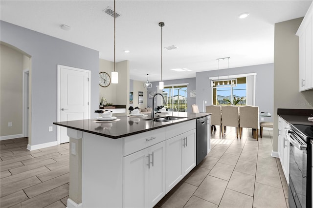 kitchen with stainless steel appliances, a kitchen island with sink, white cabinetry, sink, and pendant lighting