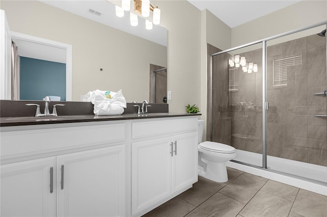 bathroom featuring double vanity, a shower with shower door, toilet, and tile flooring