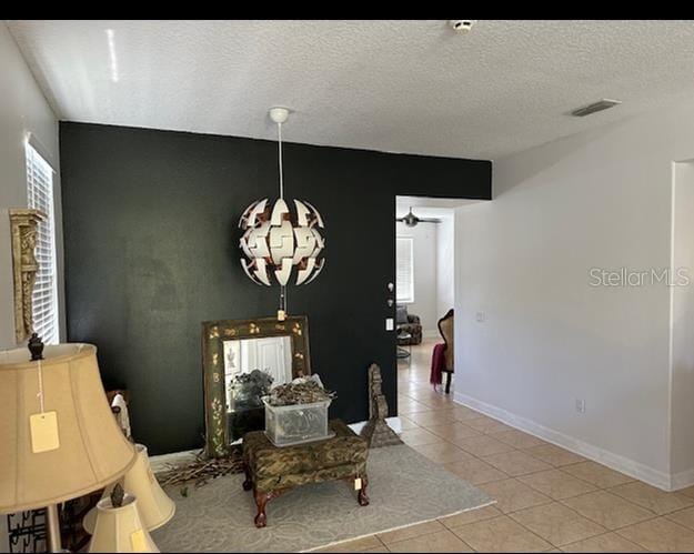 living area with a textured ceiling and light tile flooring