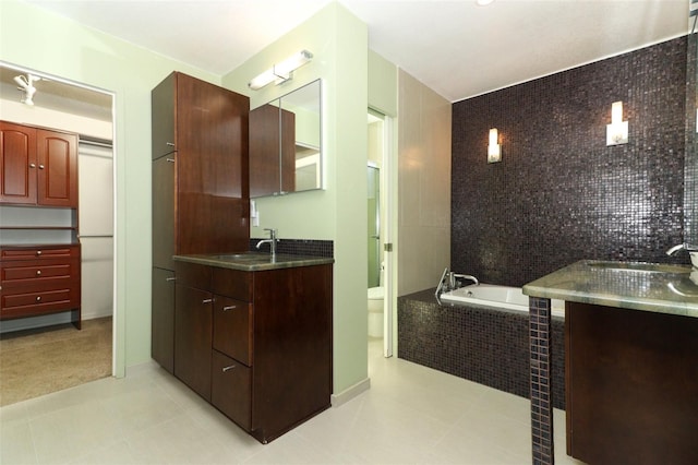 bathroom featuring tile patterned flooring, vanity, toilet, and tiled tub