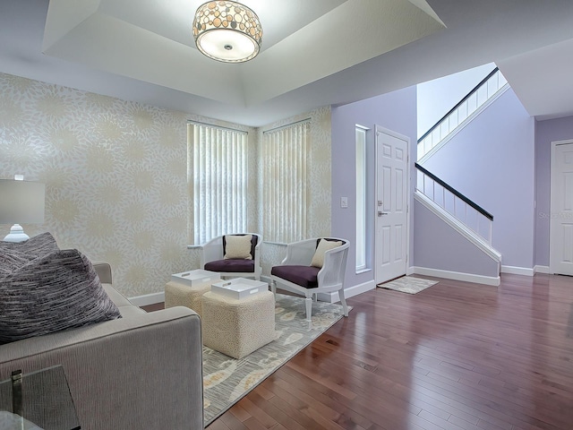 living room featuring a tray ceiling and dark wood-type flooring