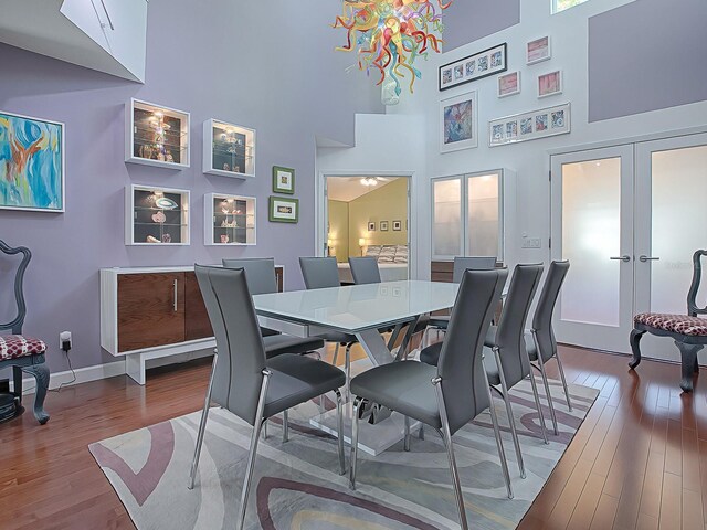 dining room with french doors, an inviting chandelier, light hardwood / wood-style flooring, and high vaulted ceiling