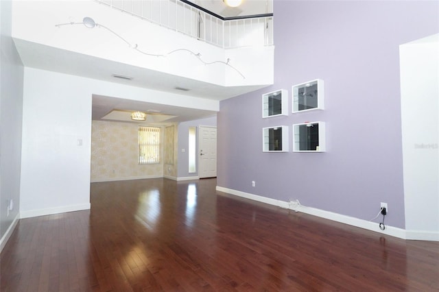 empty room featuring a high ceiling and dark hardwood / wood-style flooring