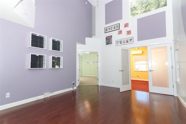 unfurnished bedroom with french doors, a towering ceiling, and dark wood-type flooring