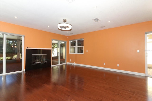 unfurnished living room featuring dark hardwood / wood-style flooring and plenty of natural light