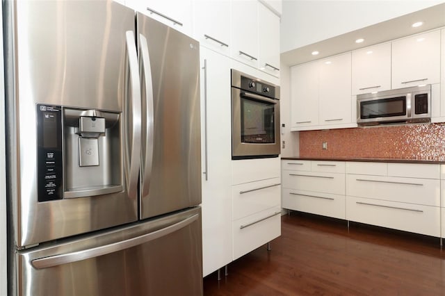 kitchen with appliances with stainless steel finishes, tasteful backsplash, white cabinetry, and dark wood-type flooring