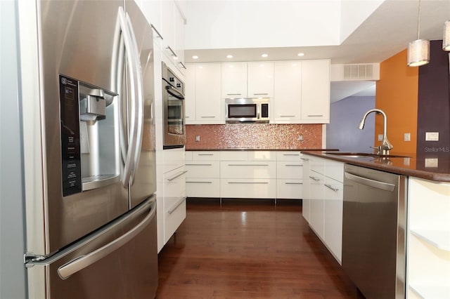 kitchen with white cabinetry, sink, stainless steel appliances, dark hardwood / wood-style floors, and decorative light fixtures