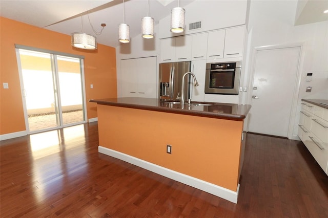 kitchen with a center island with sink, hanging light fixtures, dark hardwood / wood-style floors, appliances with stainless steel finishes, and white cabinetry