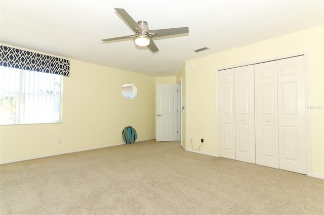 unfurnished bedroom with ceiling fan, light colored carpet, and a closet