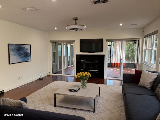 living area with wood finished floors, visible vents, baseboards, a fireplace, and recessed lighting