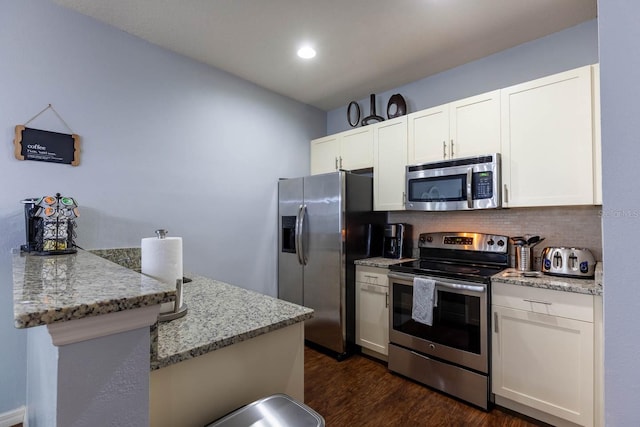 kitchen with dark hardwood / wood-style flooring, appliances with stainless steel finishes, white cabinetry, and light stone countertops