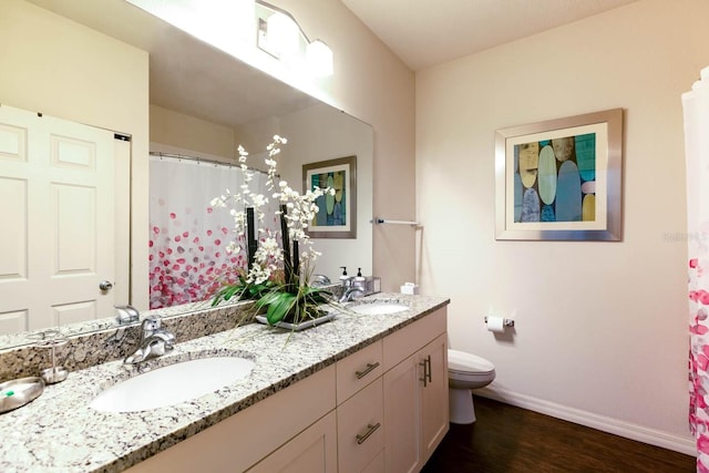 bathroom with double vanity, toilet, and hardwood / wood-style floors