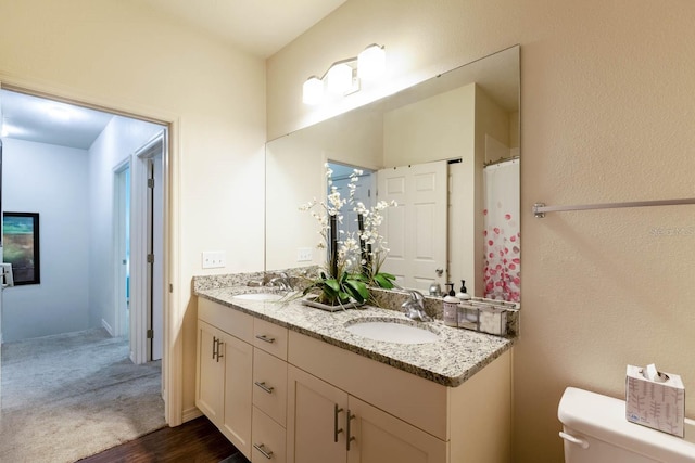 bathroom featuring toilet and dual vanity