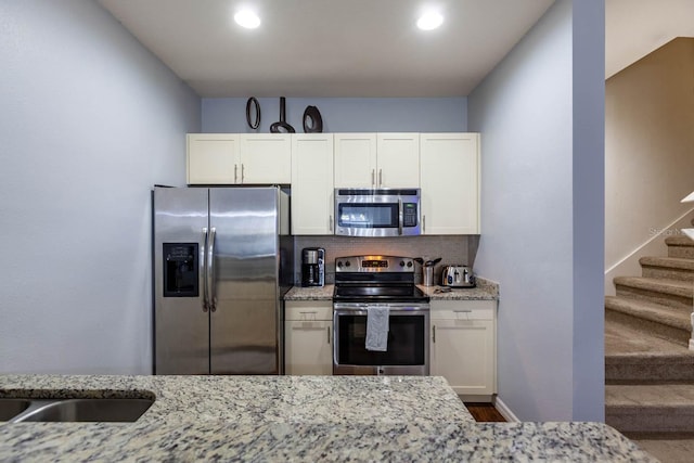 kitchen with light stone counters, appliances with stainless steel finishes, and white cabinetry