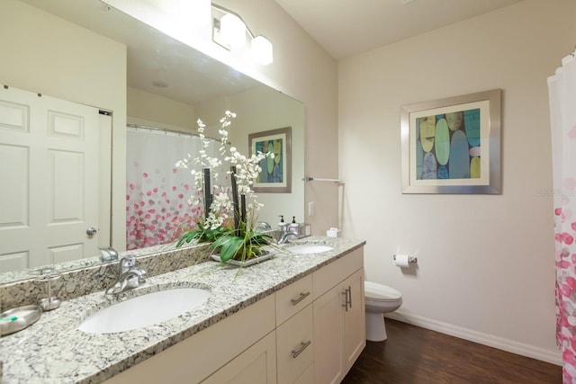 bathroom featuring hardwood / wood-style flooring, toilet, and dual vanity