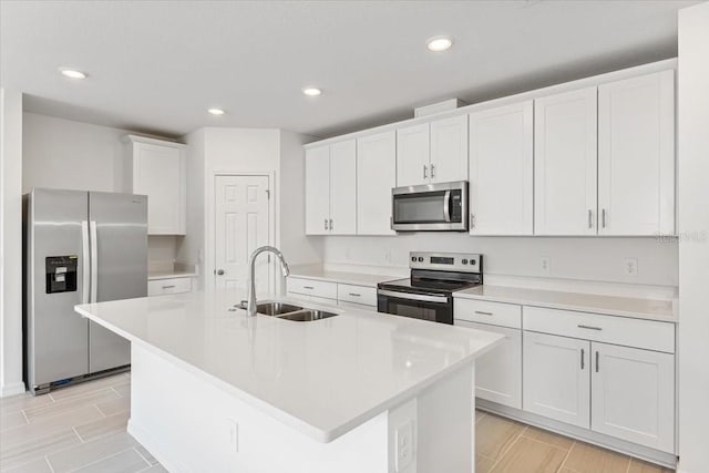 kitchen with sink, an island with sink, white cabinets, and appliances with stainless steel finishes