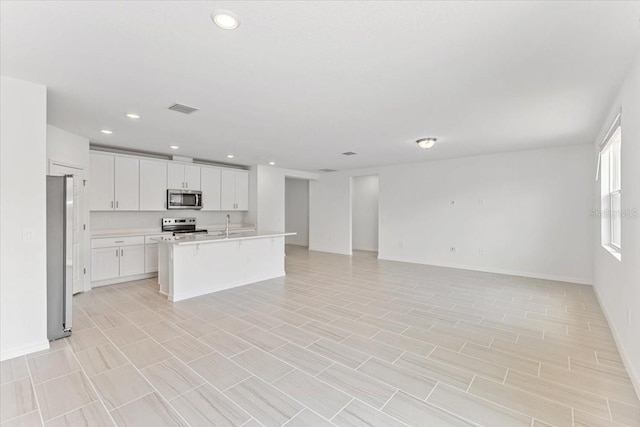 kitchen with a kitchen island with sink, sink, stainless steel appliances, and white cabinets