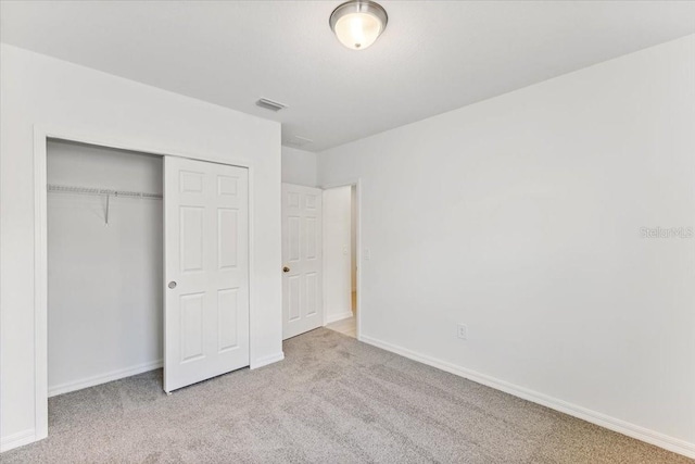 unfurnished bedroom with light colored carpet and a closet