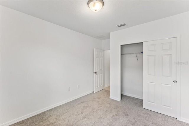 unfurnished bedroom with a closet, light carpet, and a textured ceiling