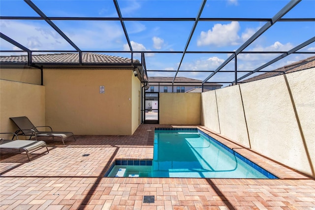 view of pool featuring a jacuzzi, a patio, and glass enclosure