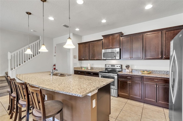 kitchen featuring light stone counters, appliances with stainless steel finishes, sink, light tile flooring, and pendant lighting