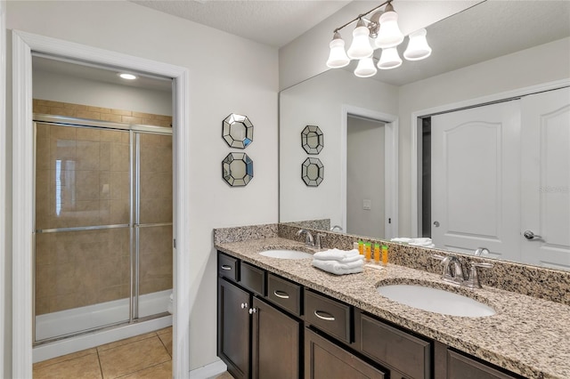 bathroom with tile flooring, large vanity, double sink, an enclosed shower, and an inviting chandelier