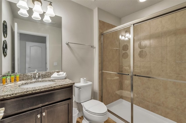 bathroom featuring a shower with door, toilet, oversized vanity, and a textured ceiling