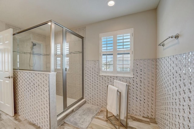 bathroom with a shower with door, tile floors, and tile walls