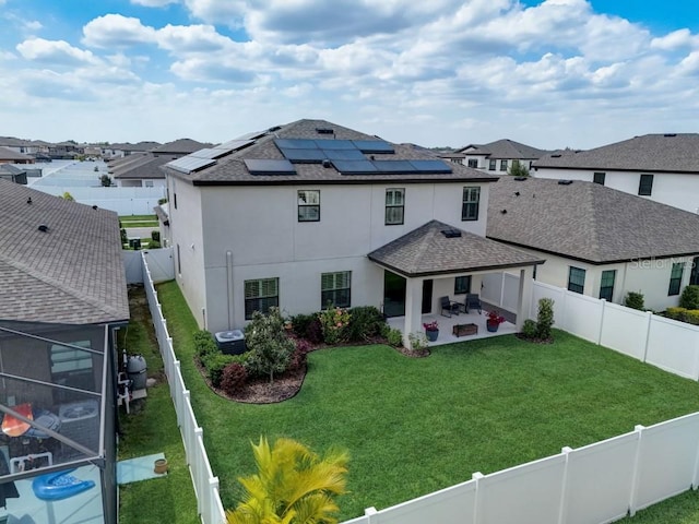 rear view of property featuring solar panels, a yard, central AC, and a patio