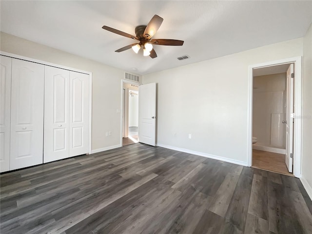 unfurnished bedroom with connected bathroom, dark wood-type flooring, a closet, and ceiling fan