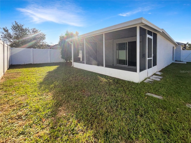 rear view of house with a yard and a sunroom