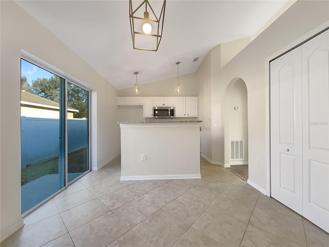 kitchen featuring light tile patterned flooring, hanging light fixtures, lofted ceiling, and white cabinets