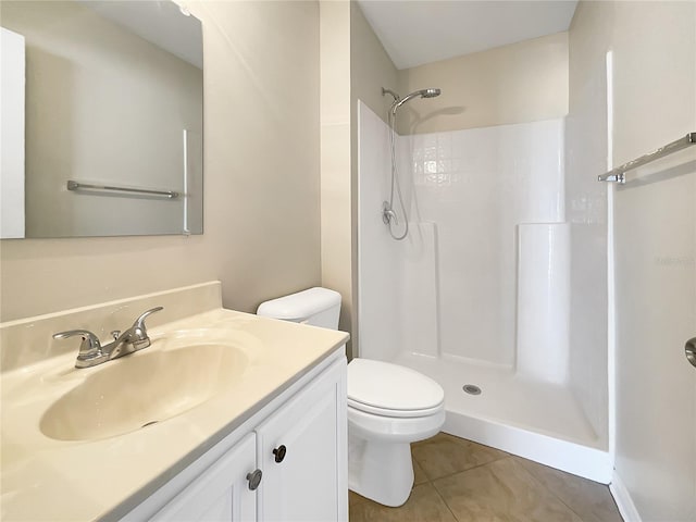 bathroom with vanity, tile patterned flooring, toilet, and walk in shower