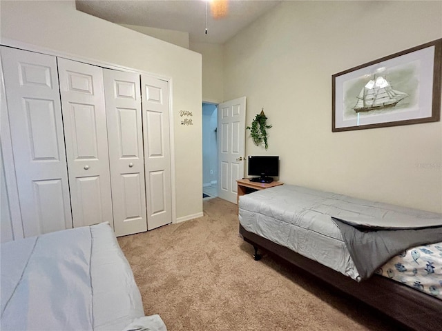 bedroom featuring ceiling fan, vaulted ceiling, light carpet, and a closet