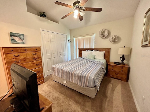 carpeted bedroom with ceiling fan, a closet, and vaulted ceiling