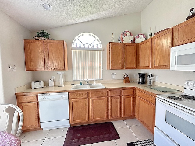 kitchen with white appliances, sink, vaulted ceiling, light tile patterned floors, and a textured ceiling