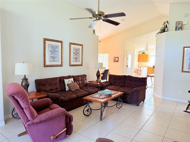 living area with ceiling fan, visible vents, baseboards, light tile patterned flooring, and high vaulted ceiling