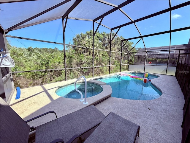 view of pool featuring glass enclosure, a pool with connected hot tub, and a patio area