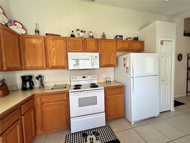 kitchen featuring light tile patterned floors, brown cabinets, white appliances, and light countertops