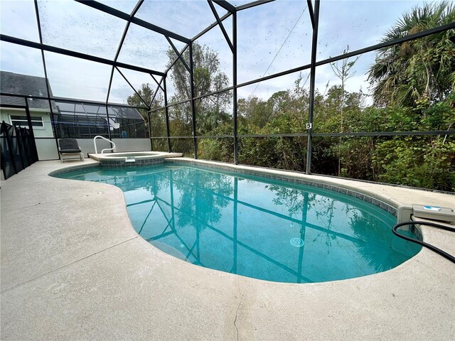 view of swimming pool with glass enclosure, a pool with connected hot tub, and a patio area