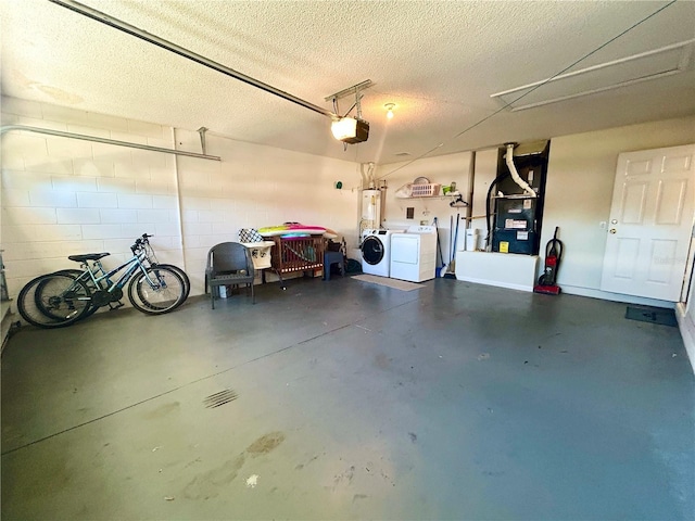 garage featuring heating unit, water heater, washing machine and clothes dryer, a garage door opener, and concrete block wall