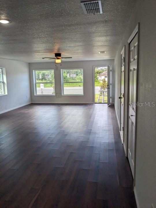 empty room with dark hardwood / wood-style floors, a healthy amount of sunlight, and a textured ceiling