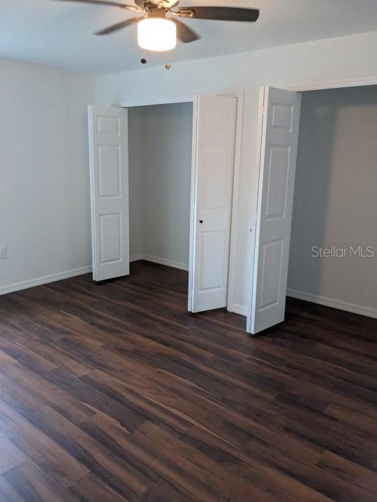 unfurnished bedroom featuring dark hardwood / wood-style floors and ceiling fan