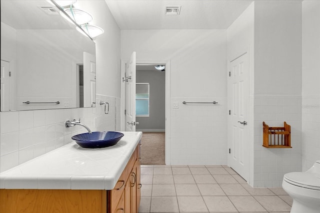 bathroom with vanity, toilet, tile floors, and tile walls